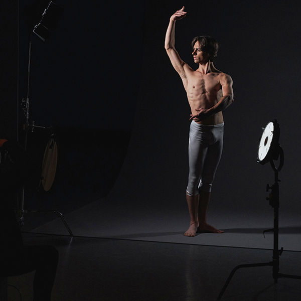 Image of male ballet dancer posing for photograph on darkened stage