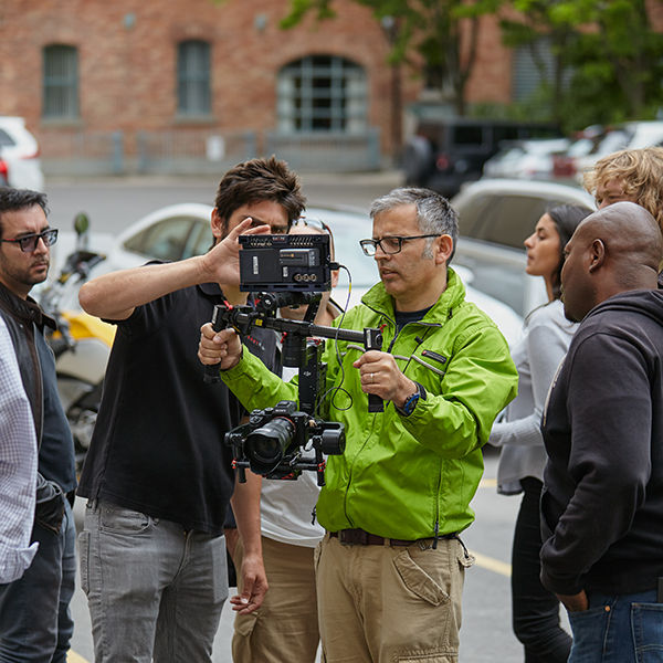 Image of man holding gimbal in front of other people